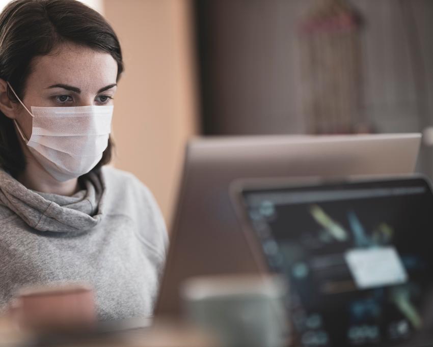 Frau mit Mund-Nasen-Bedeckung am PC